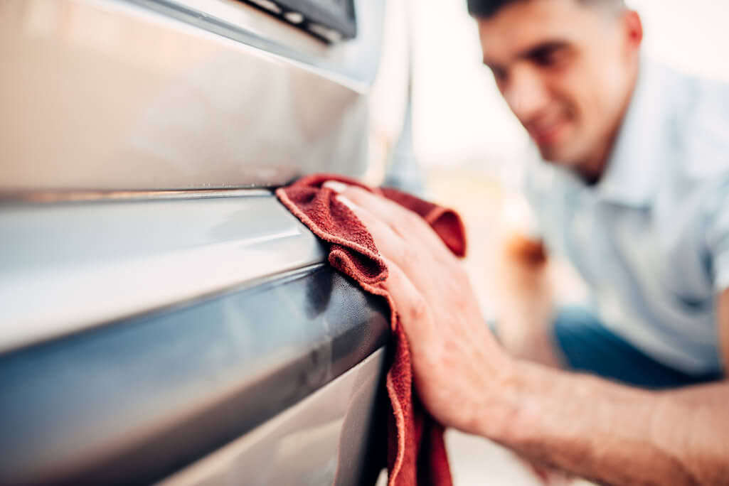 man using microfiber cloth to apply waterless car wash