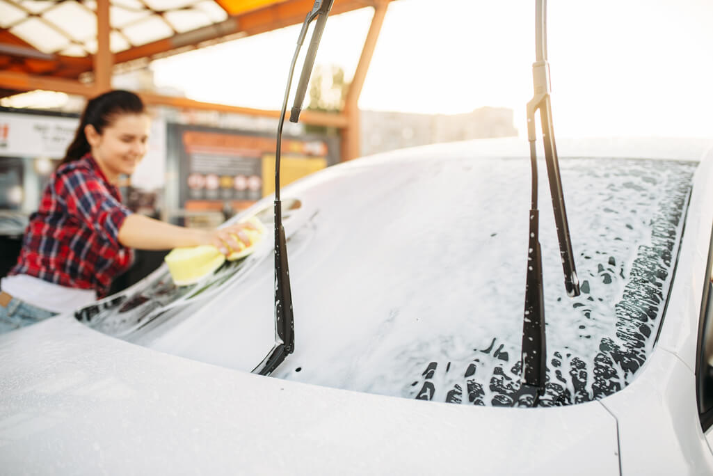 young girl learning how to hand wash a car