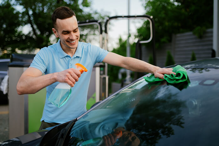 Man using window cleaner and a rag, hand auto wash